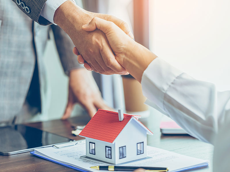 Leistungen für Verkäufer/innen Zwei Menschen geben sich die Hand über einem erfolgreichen Immobilienverkauf